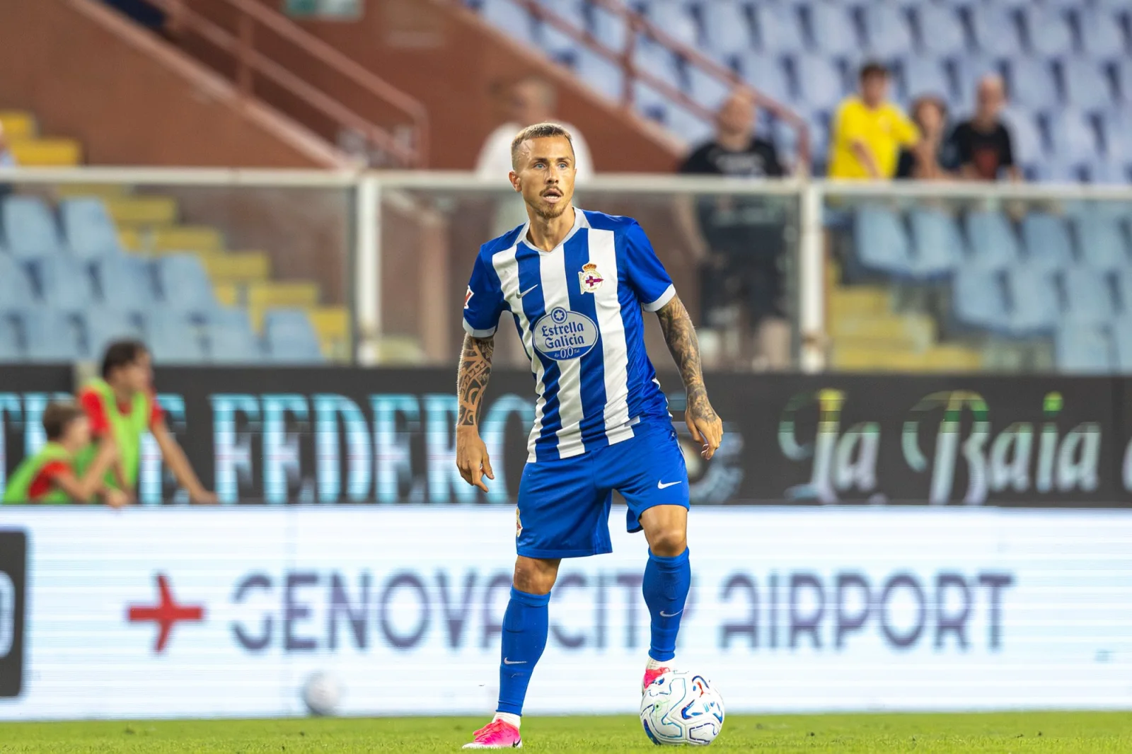 Angeliño disputa un balón con la camiseta blanquiazul del Deportivo sobre el césped.