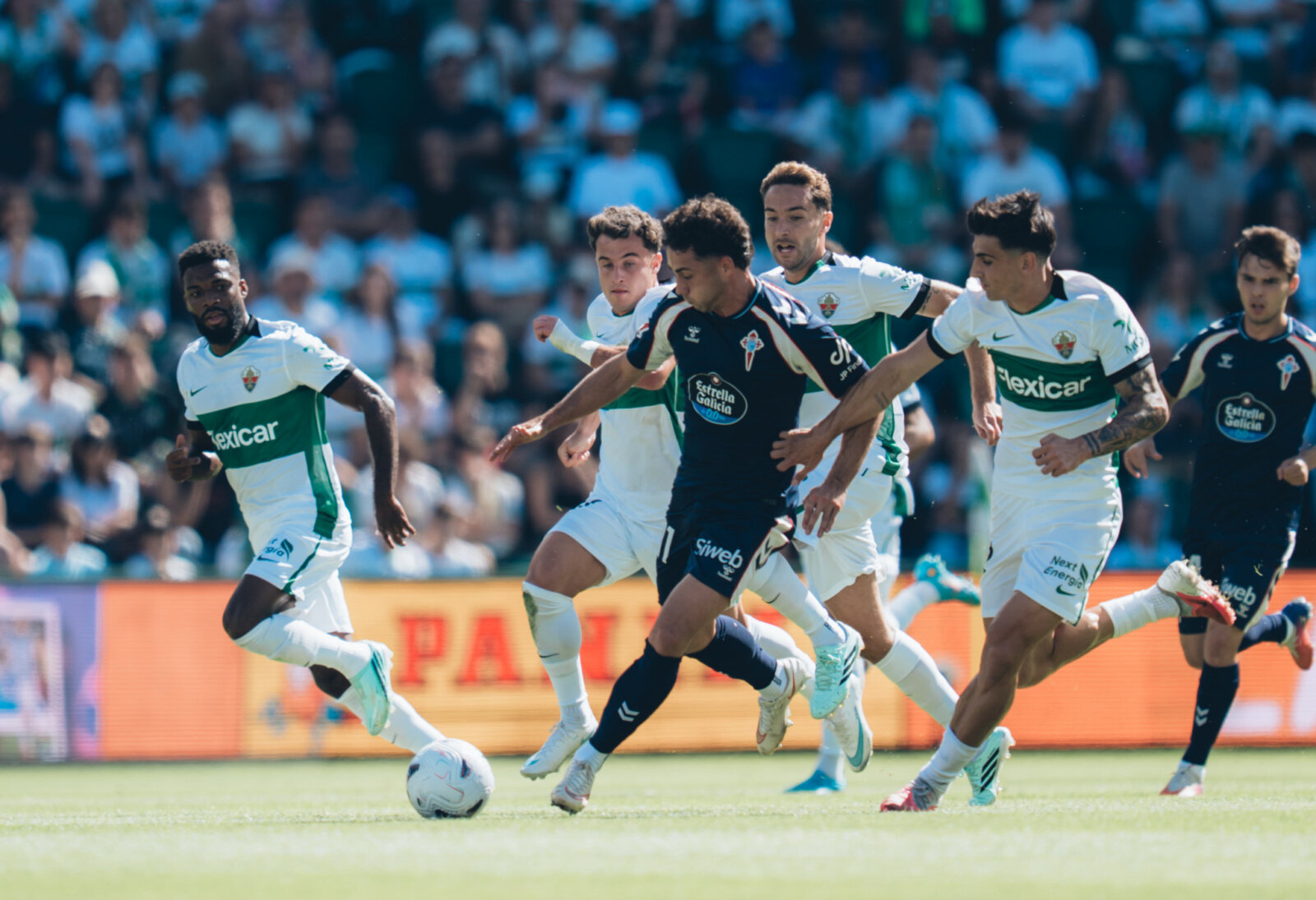 Un jugador del Celta avanza con el balón entre futbolistas del Elche en el Martínez Valero
